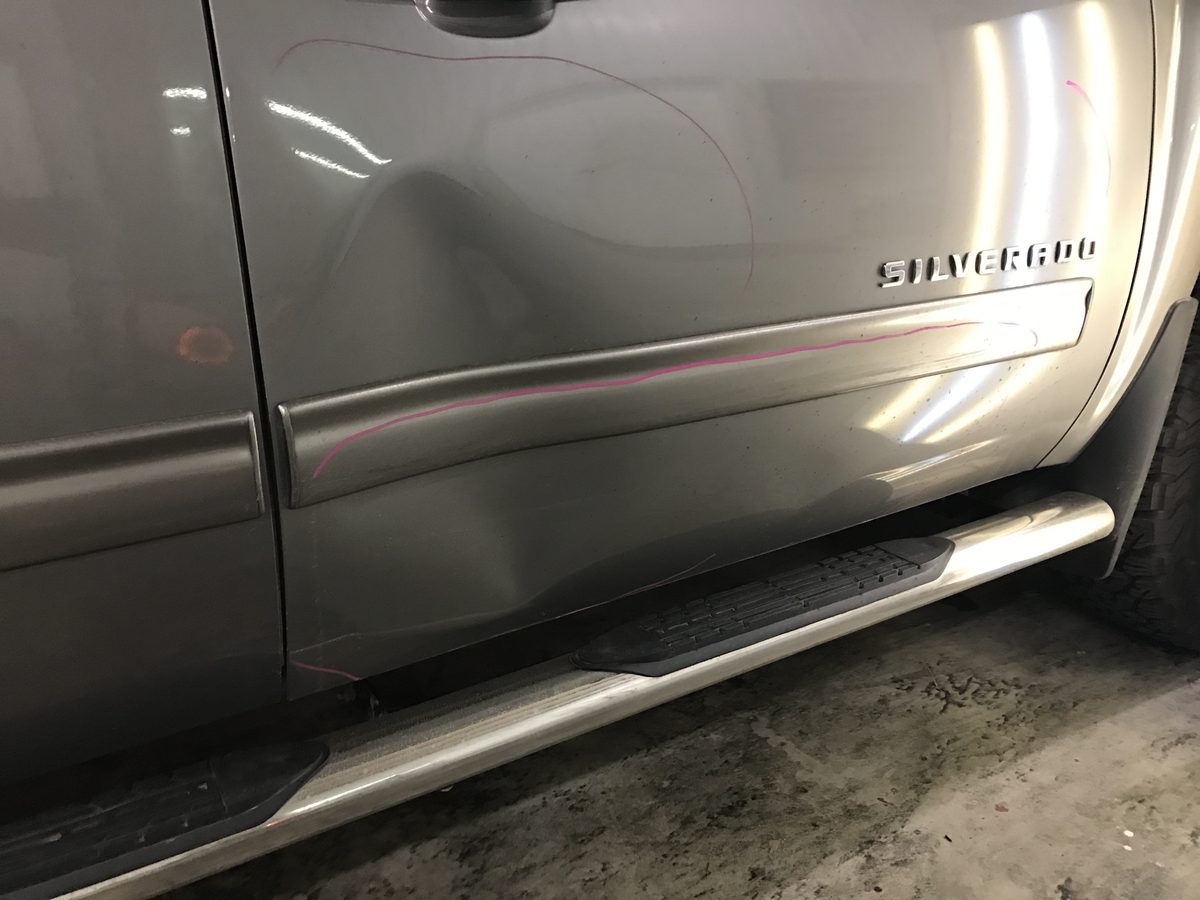 Dent damage on a 2013 Chevrolet Silverado door before paintless dent repair